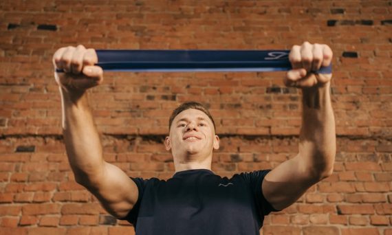 Man performing workout with resistance band against a brick wall backdrop.